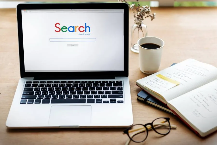 Laptop showing a search engine next to a cup of coffee